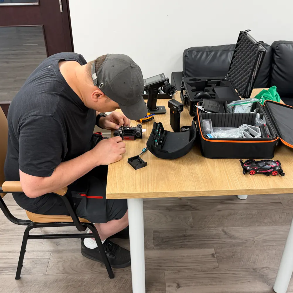 Racer preparing a 1/12 scale on-road chassis in the pit area