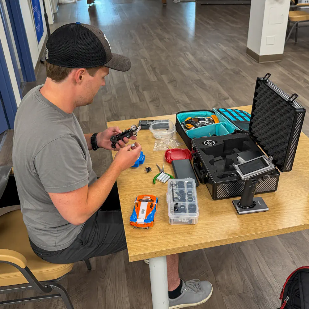 Racer working on an RC car chassis between heats at the pit table